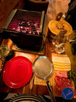 Traditional raclette dinner in Amsterdam with melted cheese, cured meats, pickles, and wine on a wooden table.